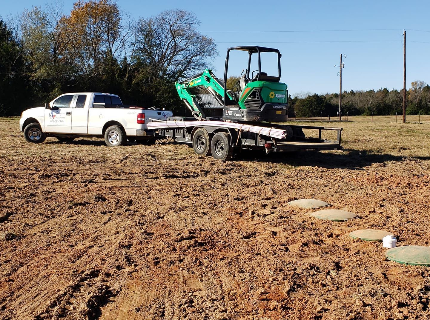 a white truck is parked next to a trailer with a green excavator on it