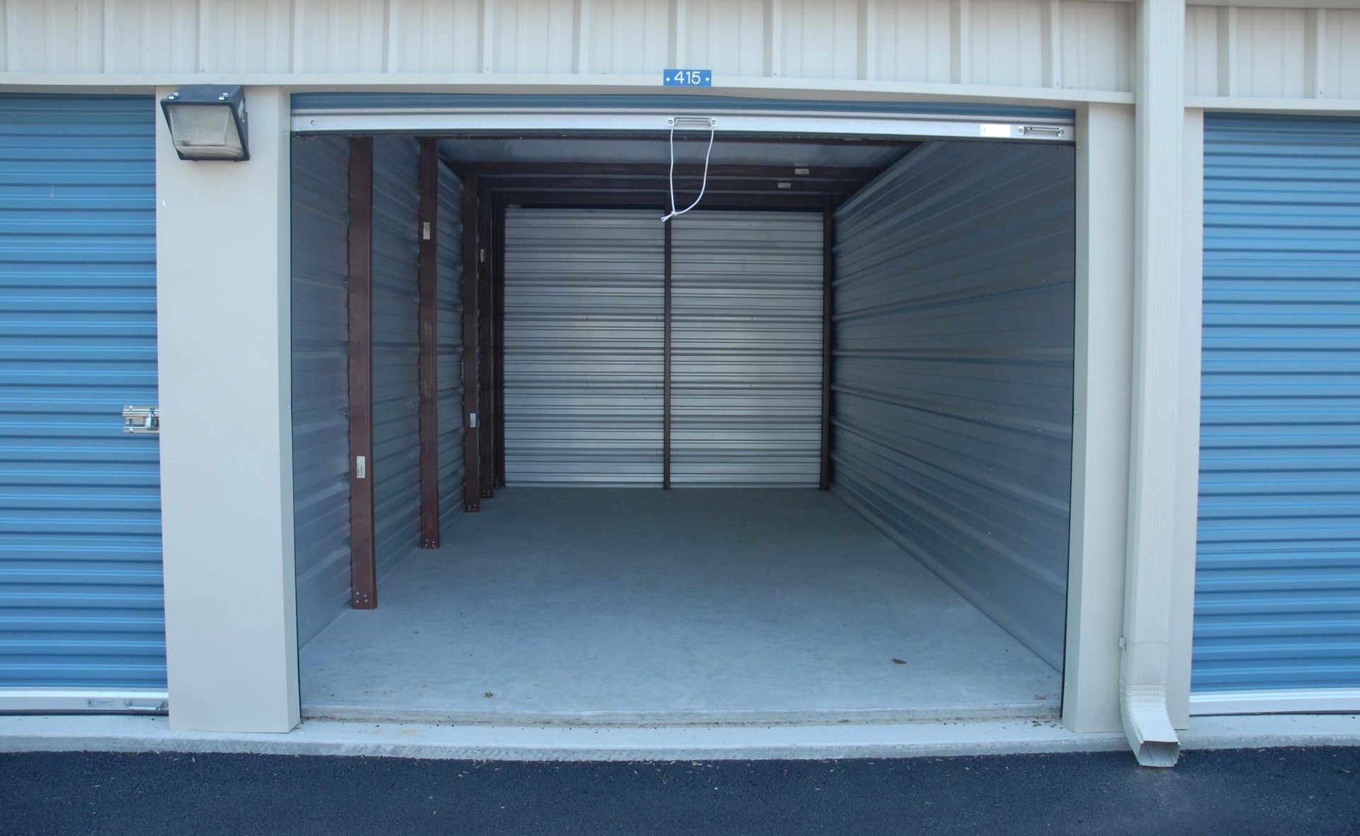 An empty storage unit with blue doors and a light on the side.