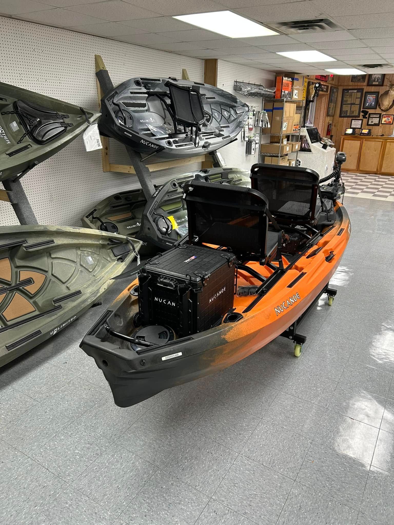 Orange and black kayak in a store, other boats in the background.