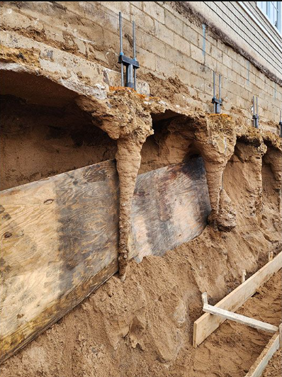 a brick wall with a lot of dirt and a wooden plank in front of it .