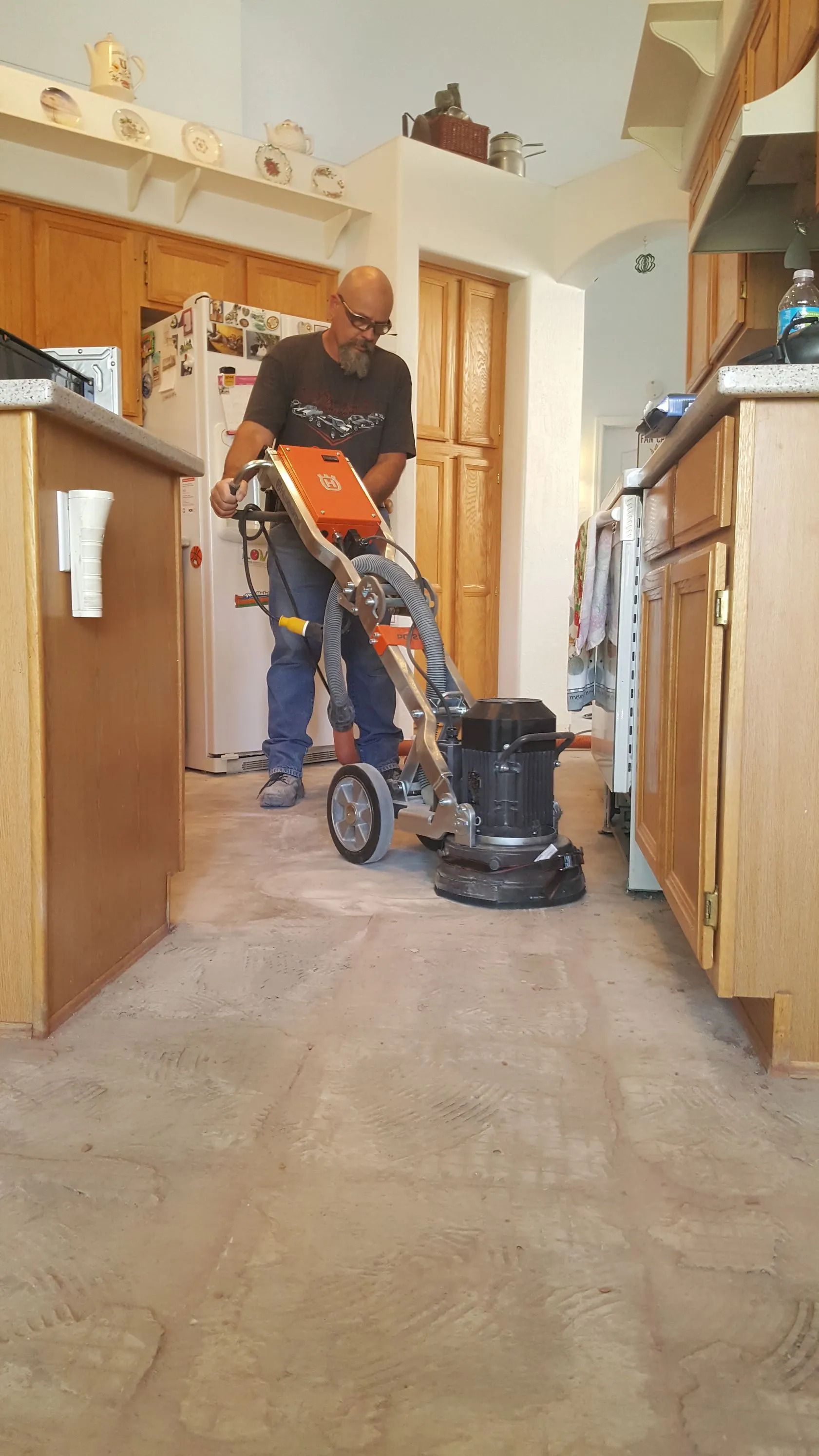 A man is using a vacuum cleaner to clean the floor in a kitchen.