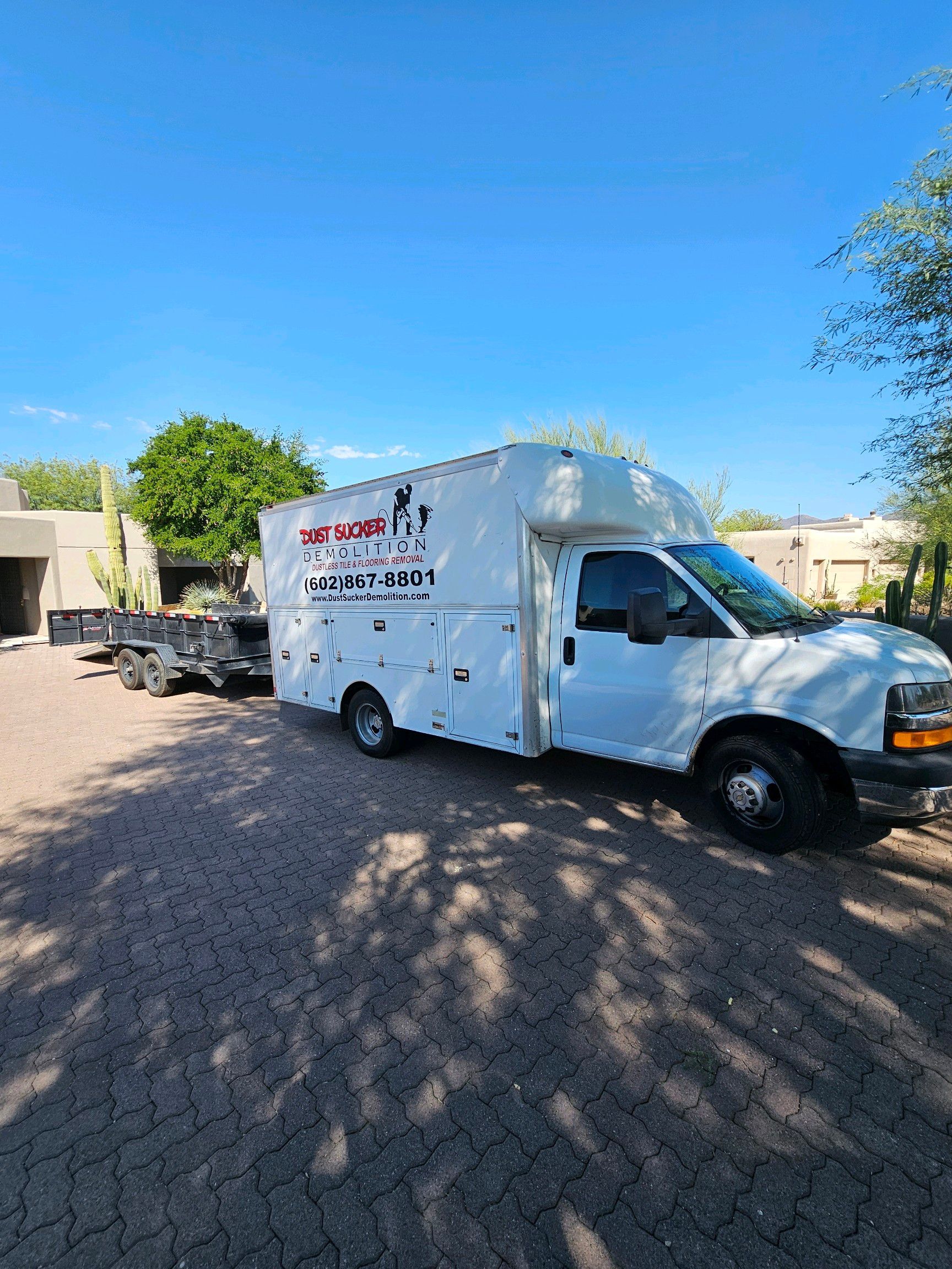 A white van is parked in a driveway next to a trailer.