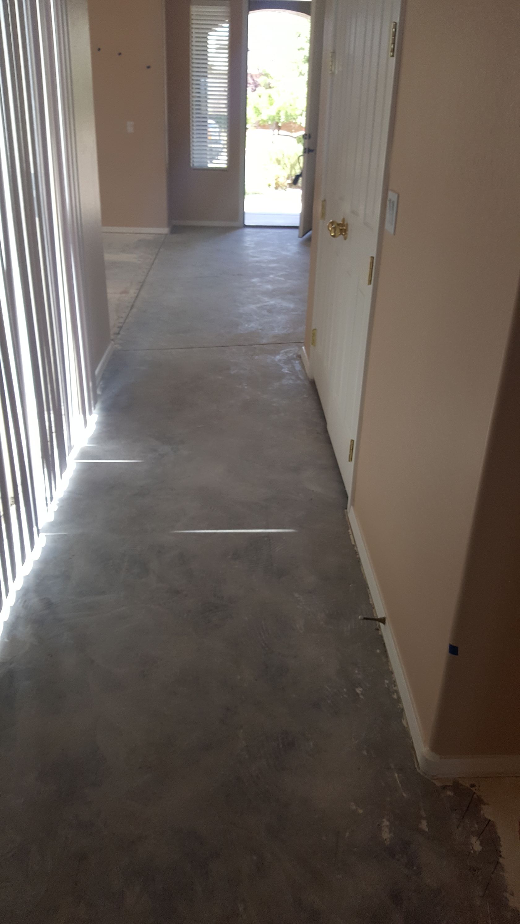 A hallway in a house with a concrete floor and a door.