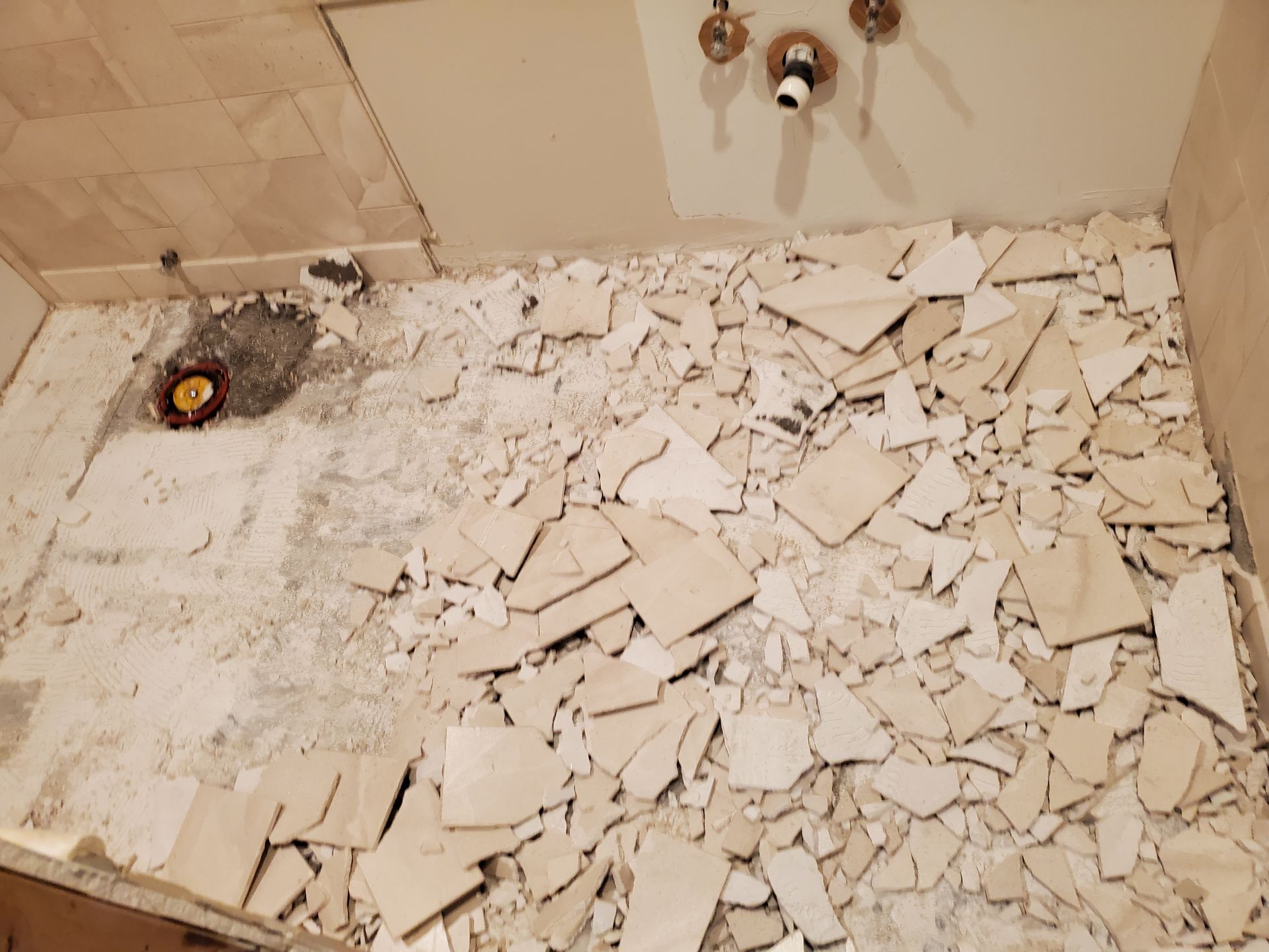 A bathroom floor with a lot of broken tiles on it.