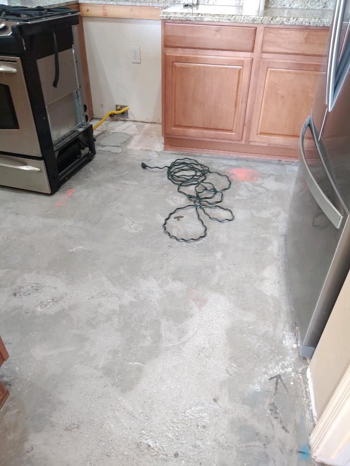 A kitchen with a stove and a refrigerator and a cord laying on the floor.