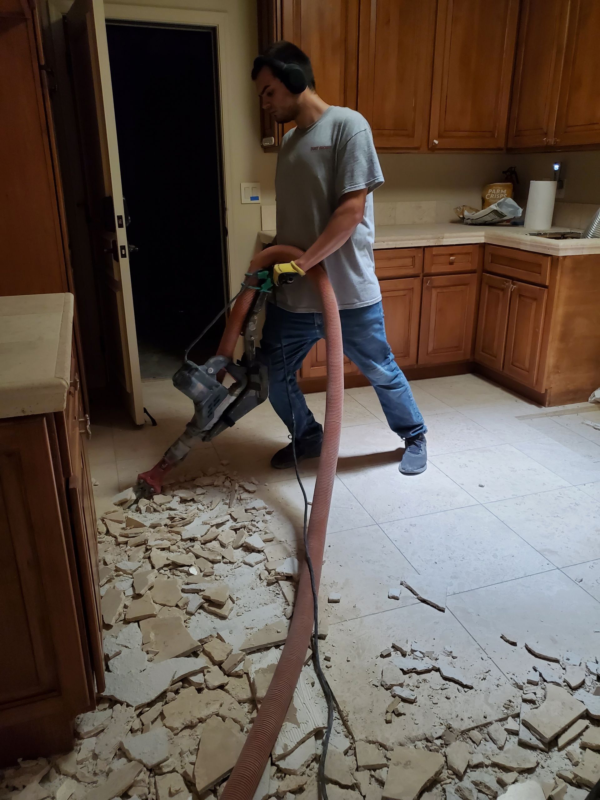 A man is using a vacuum cleaner to clean a kitchen floor.