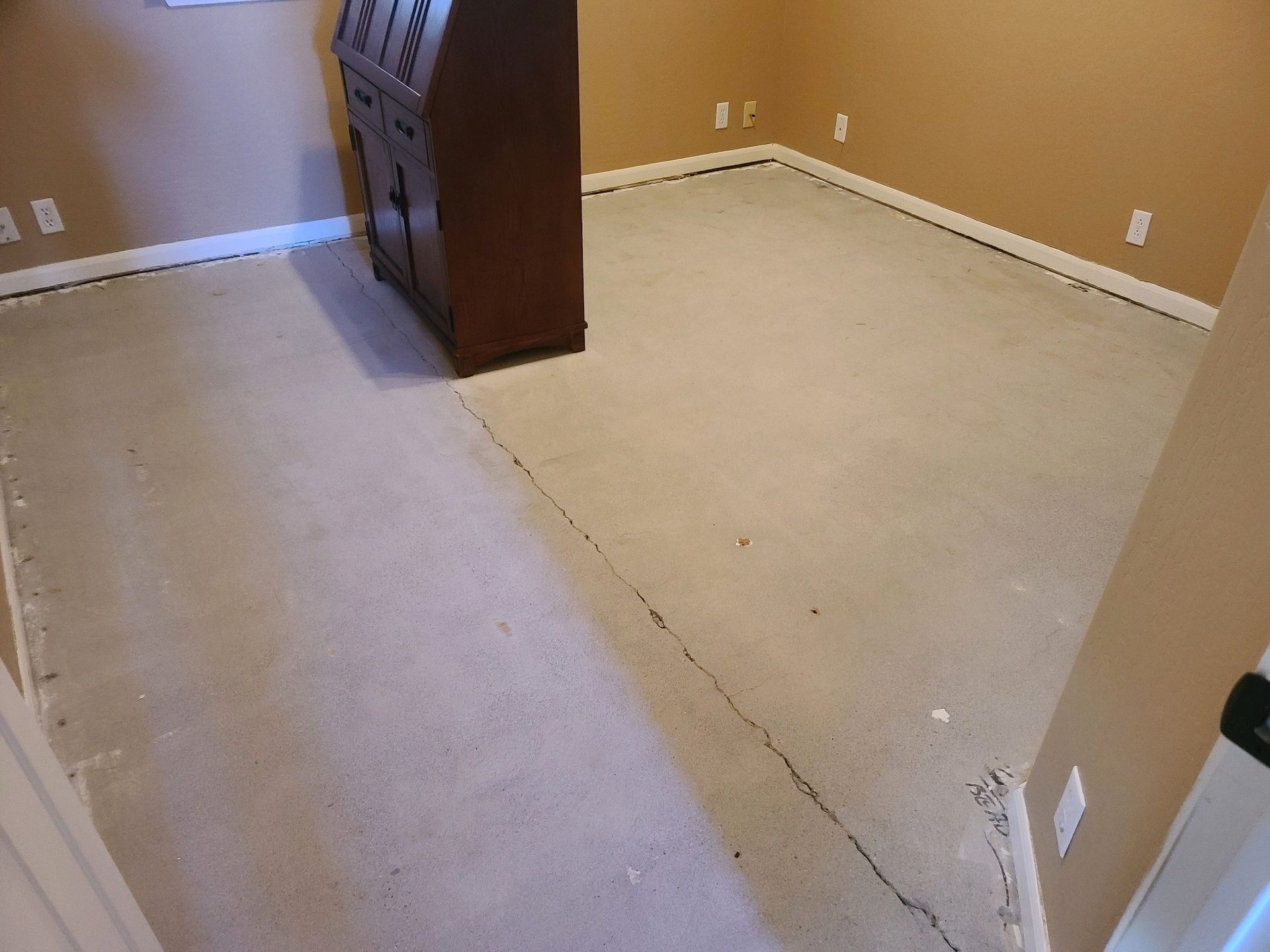 A room with a carpeted floor and a wooden cabinet.