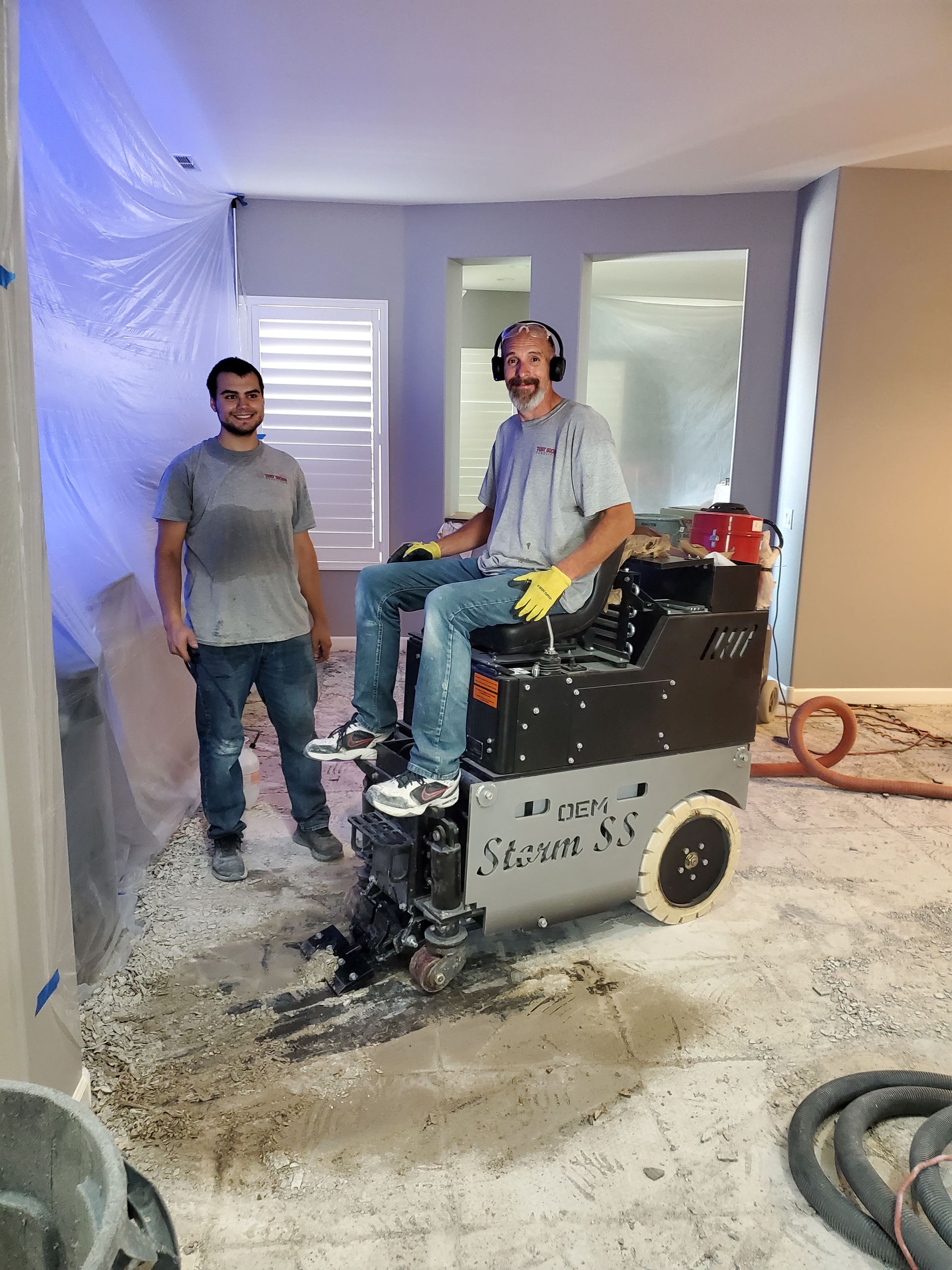 Two men are standing next to a machine in a room.