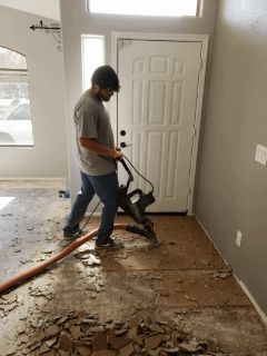 A man is using a vacuum cleaner to clean the floor in a living room.
