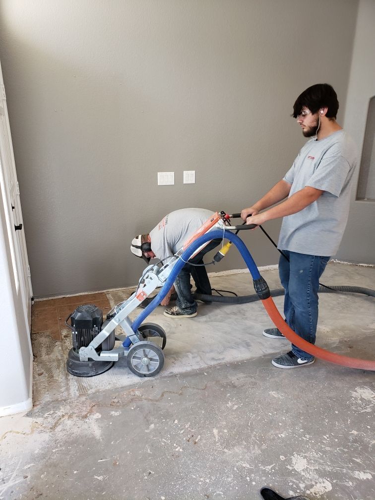 Two men are working on a floor with a machine.