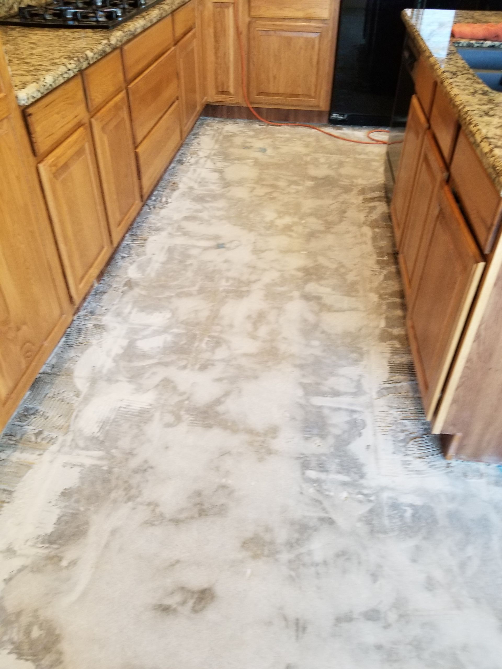 A kitchen with a concrete floor and wooden cabinets.