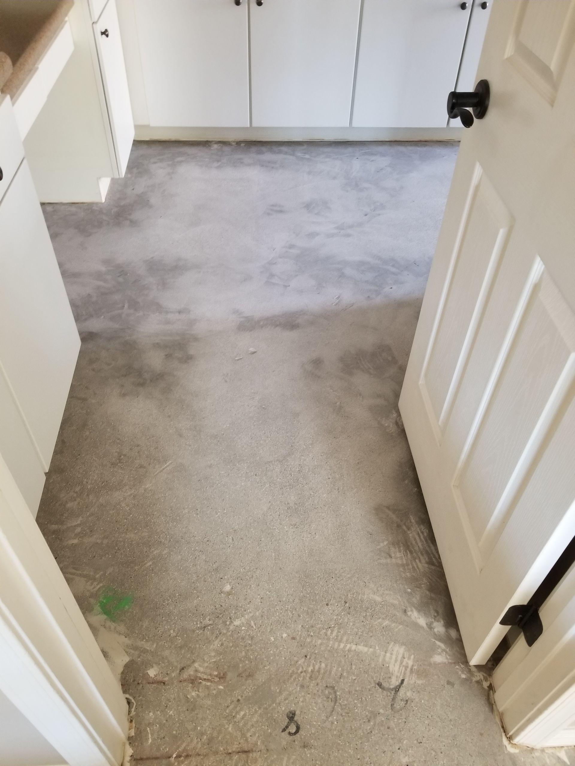 A kitchen with a dirty floor and white cabinets