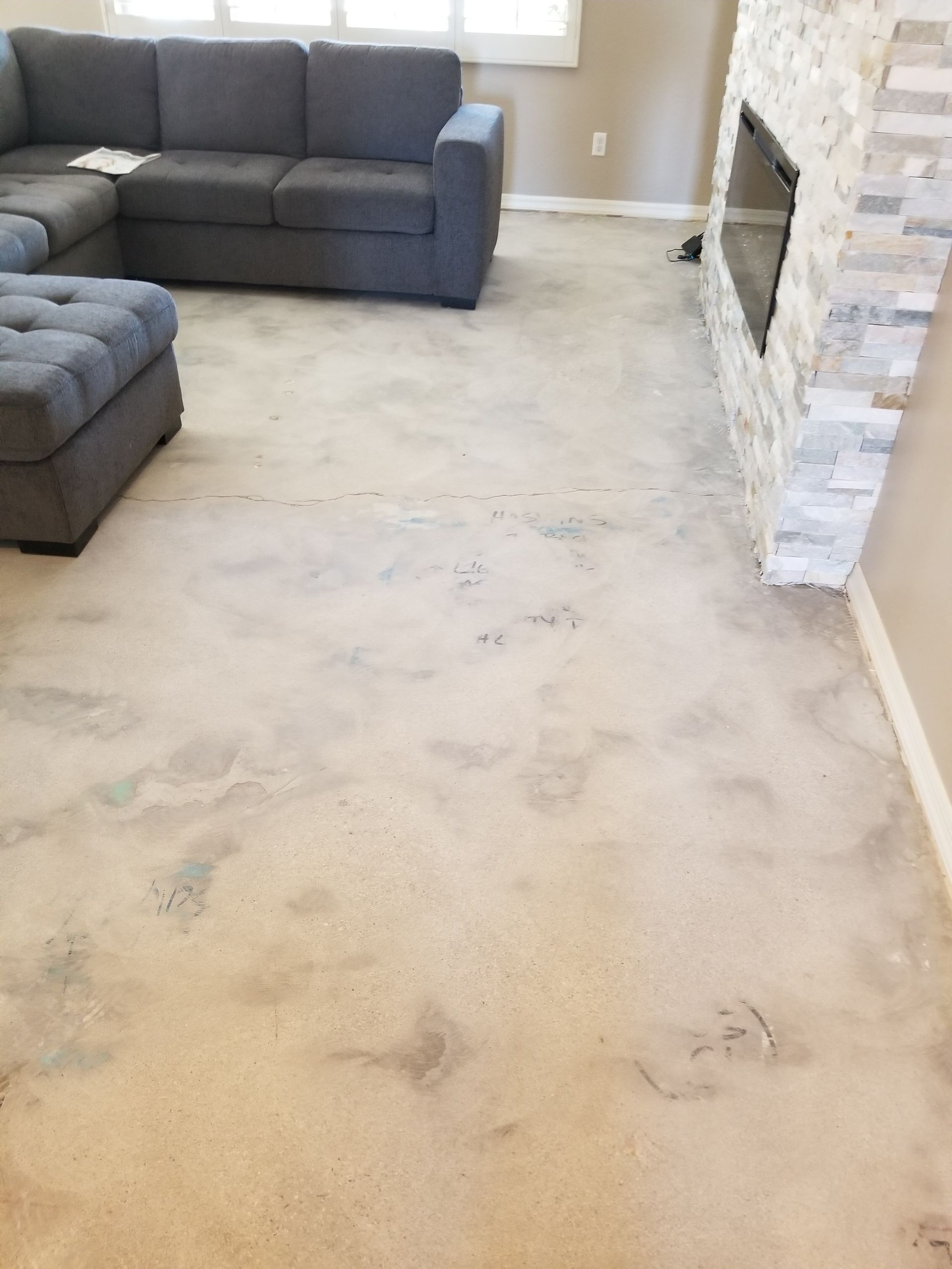 A living room with a couch, ottoman and fireplace.