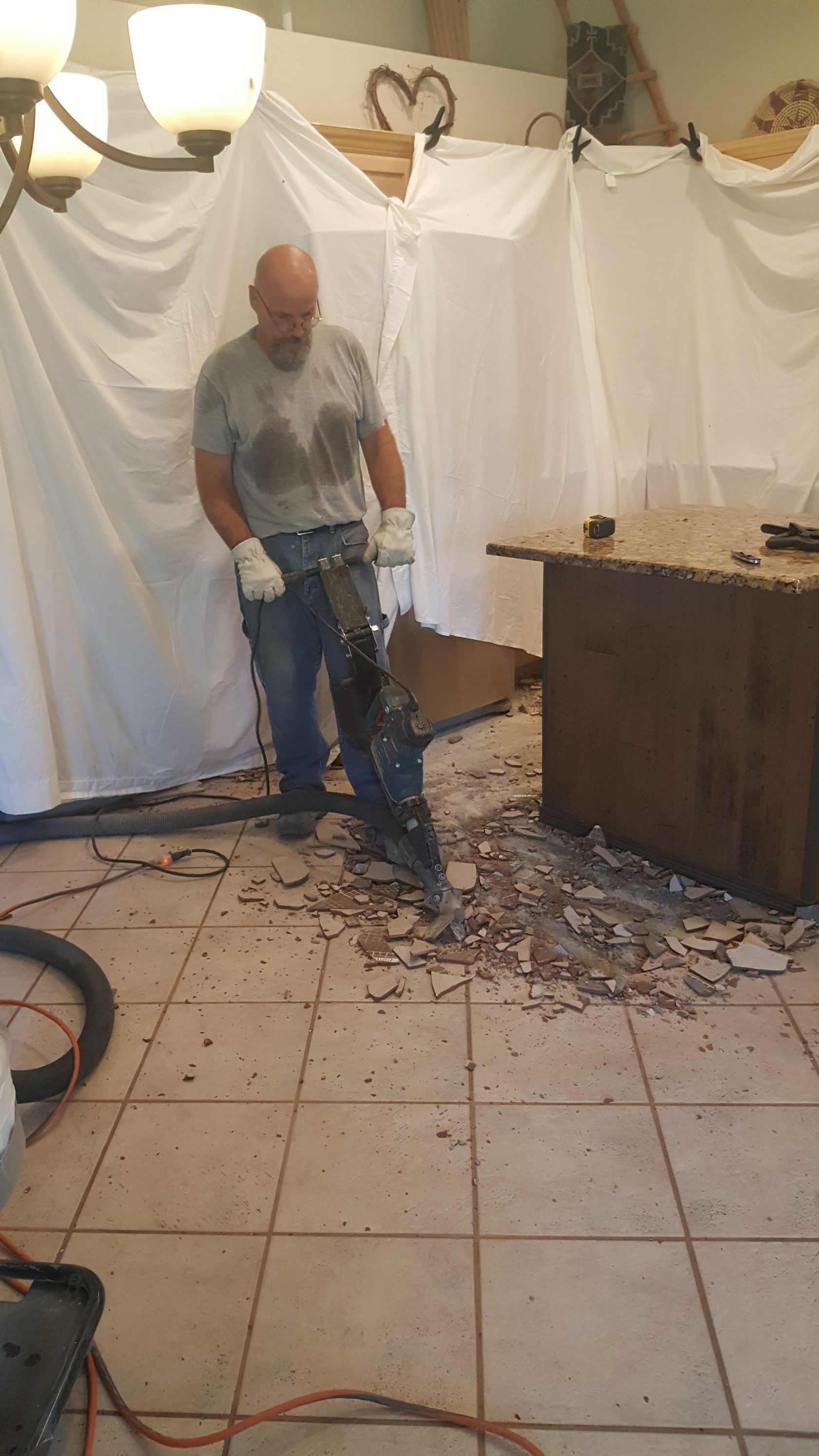 A man is using a hammer to break a table in a room.