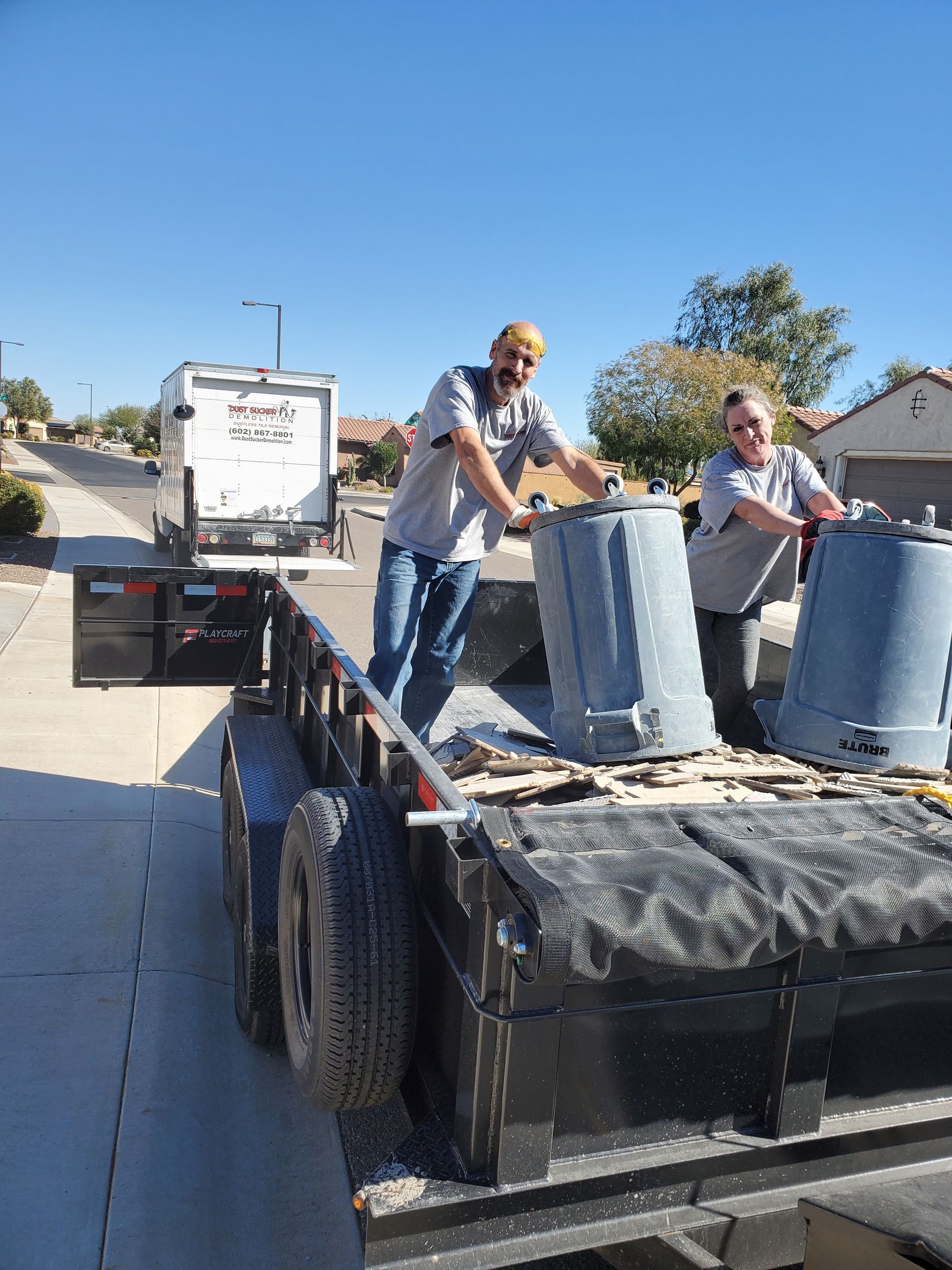 Two men are loading buckets onto a trailer.