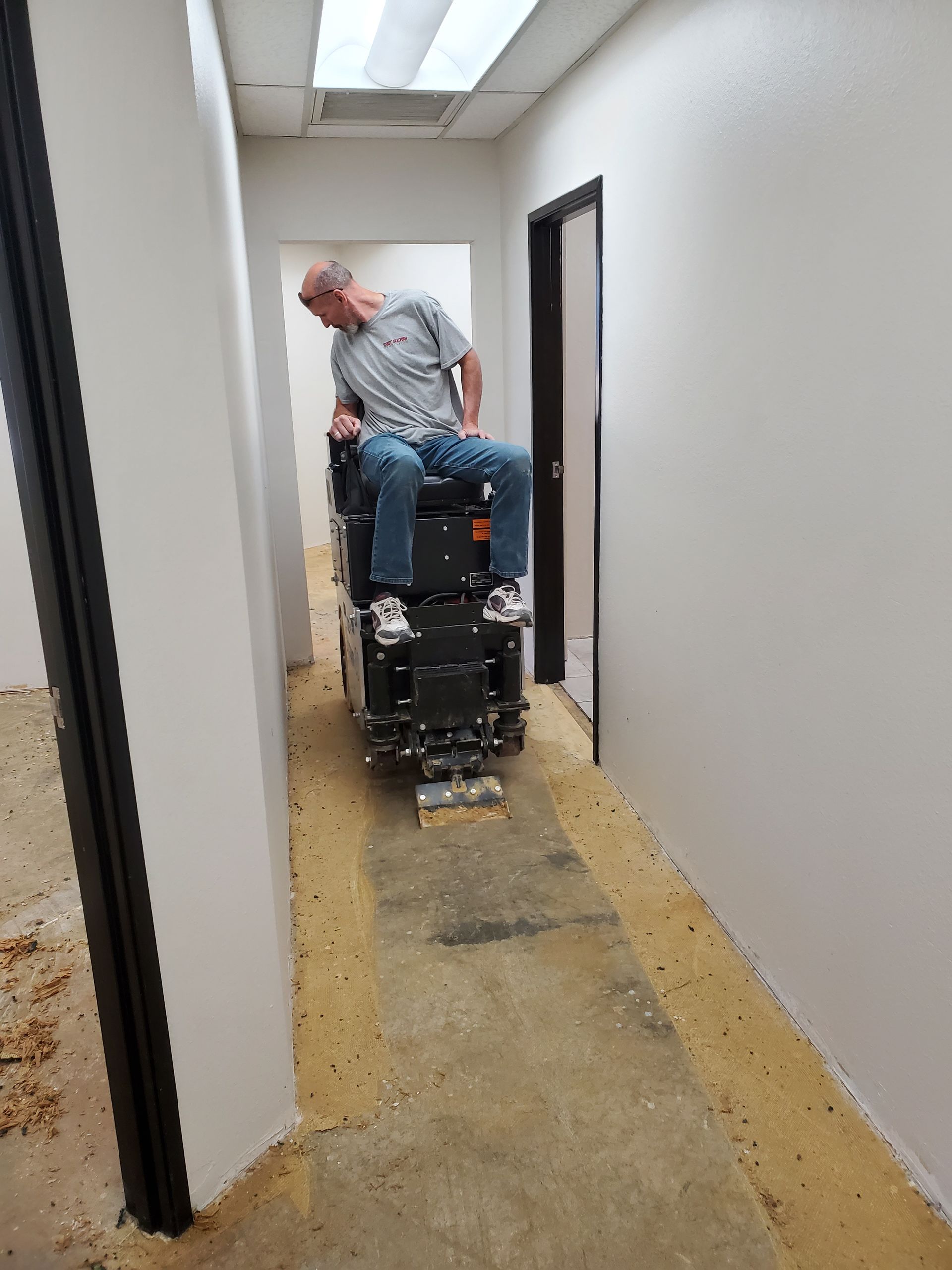 A man is sitting on a machine in a hallway.