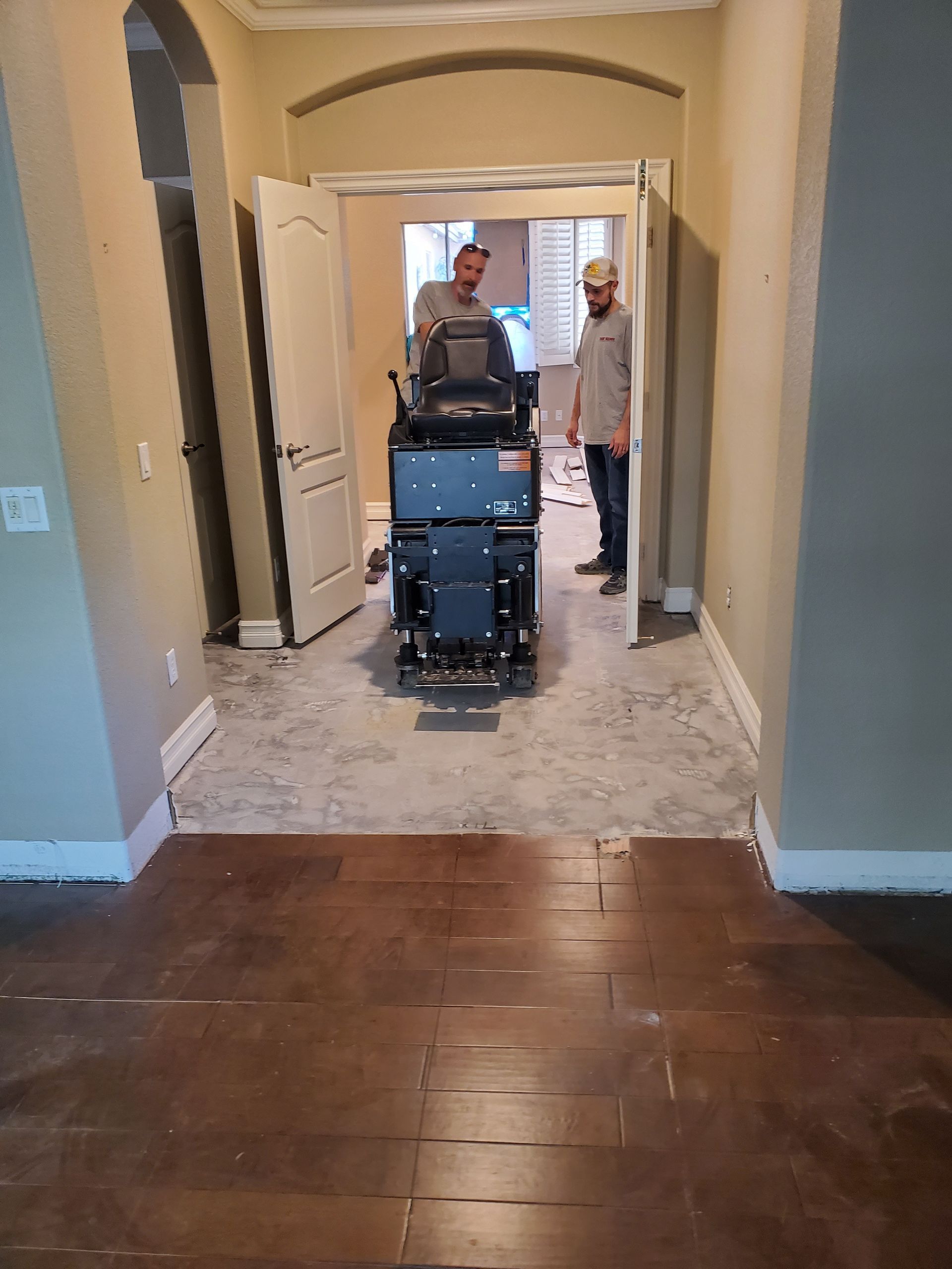 Two men are standing in a hallway next to a machine.