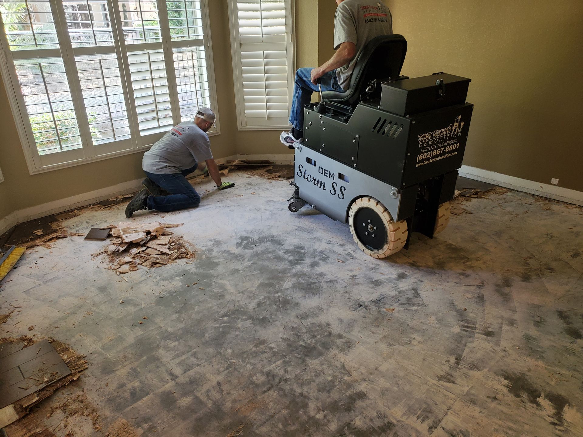 Two men are working on a carpet in a living room.