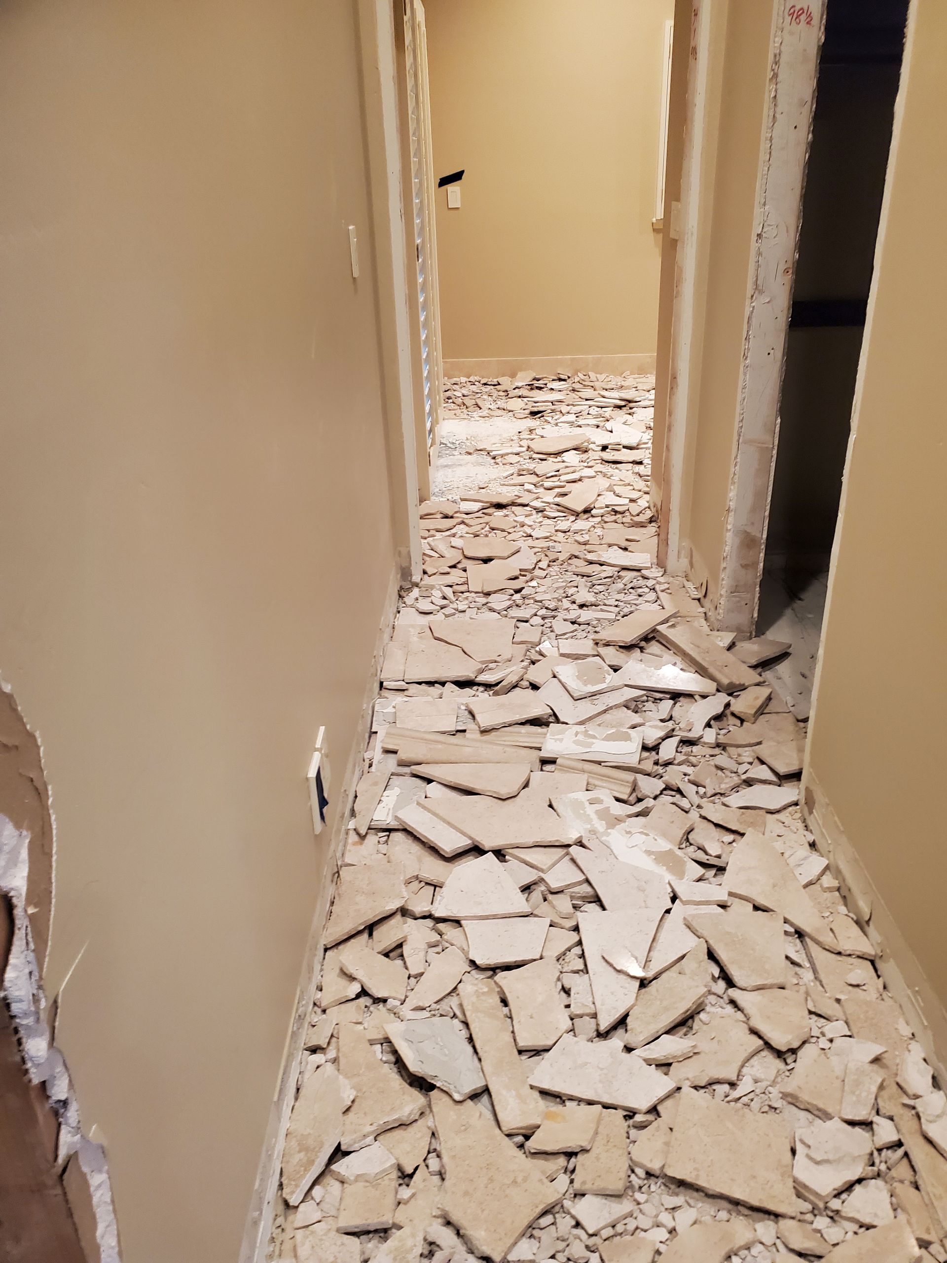 A hallway with a lot of broken tiles on the floor.