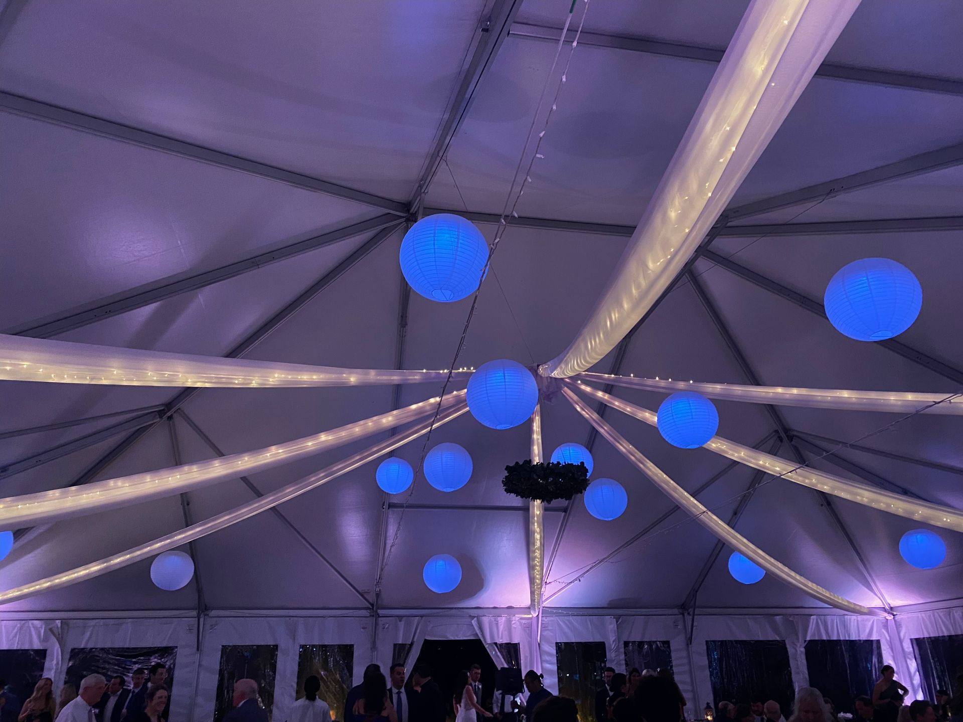 A tent interior decorated with blue orbs and white fabric, illuminated with purple lighting.