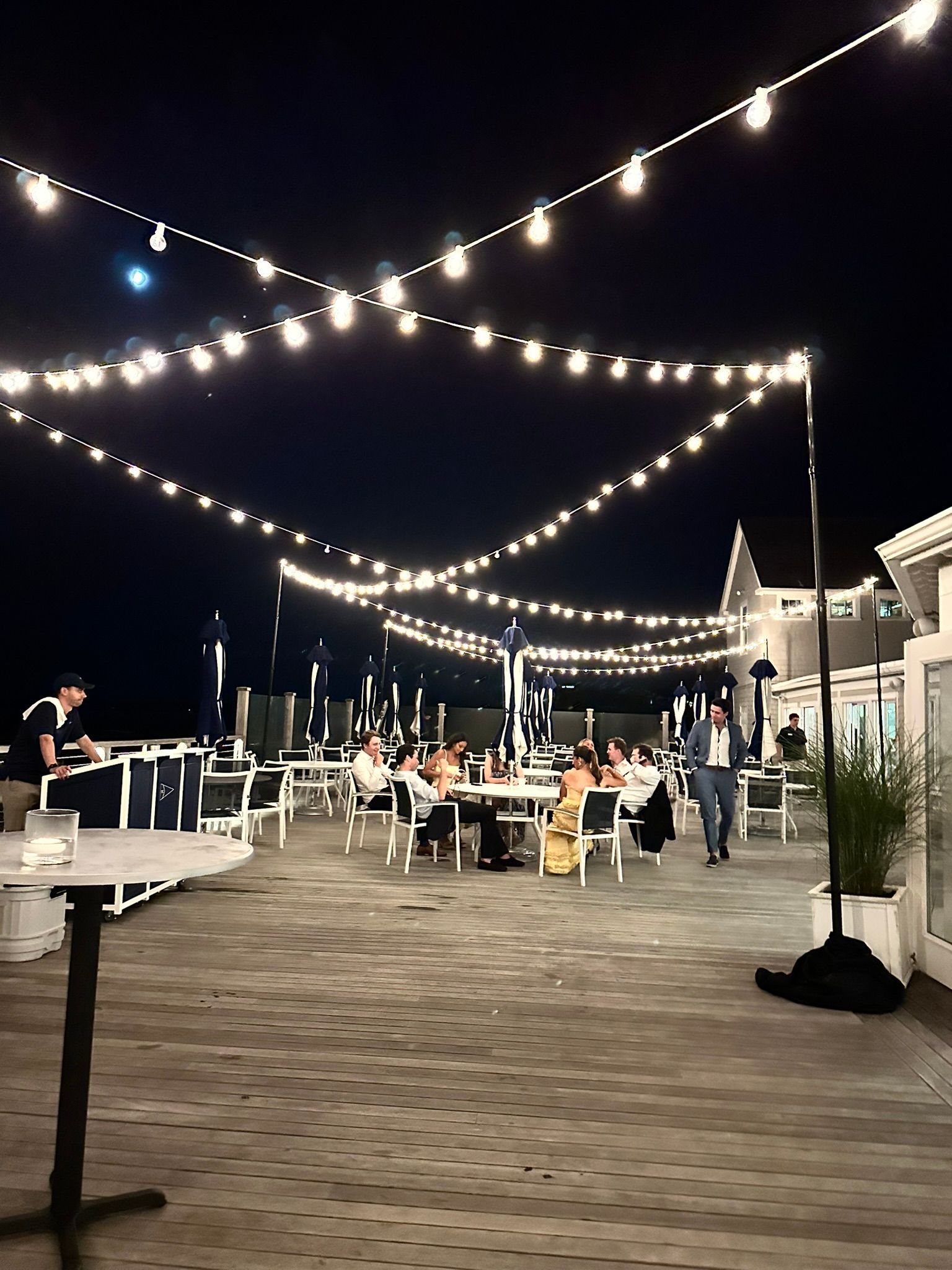 Outdoor patio at night, strung with lights, people dining at tables.