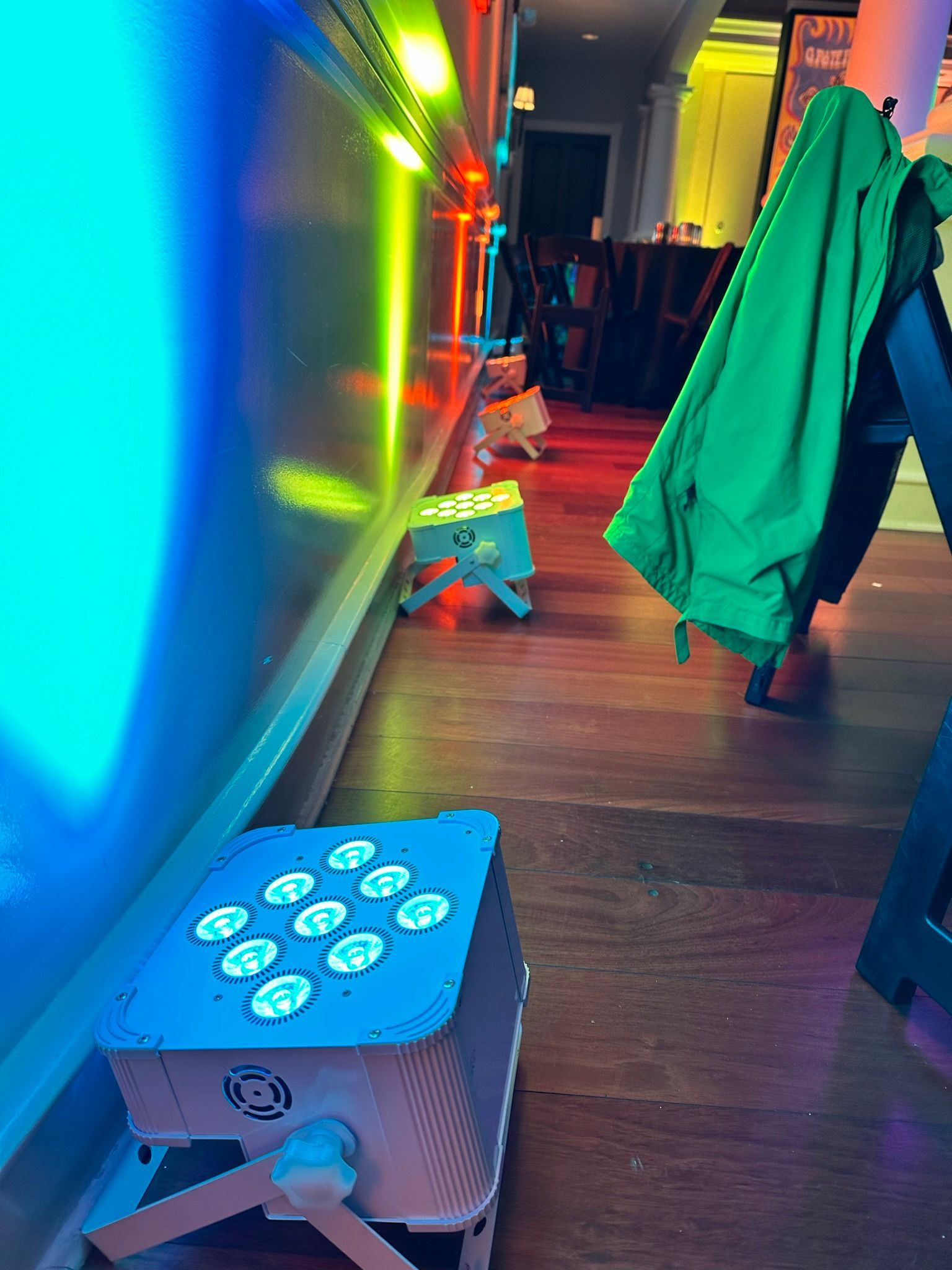 Colorful LED lights illuminate a hallway; green jacket hangs on a chair.