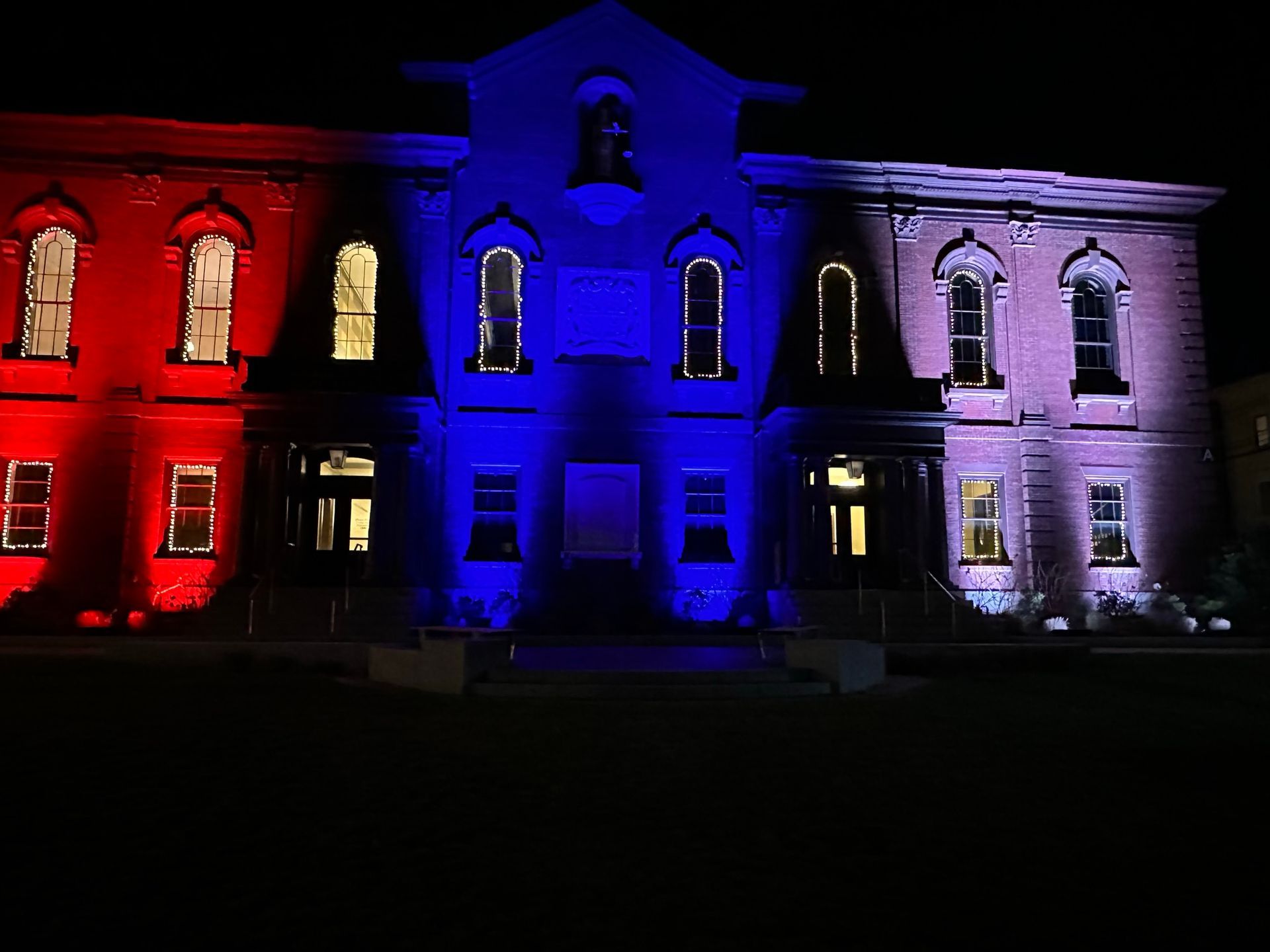 Building illuminated with red, white, and blue lights at night.