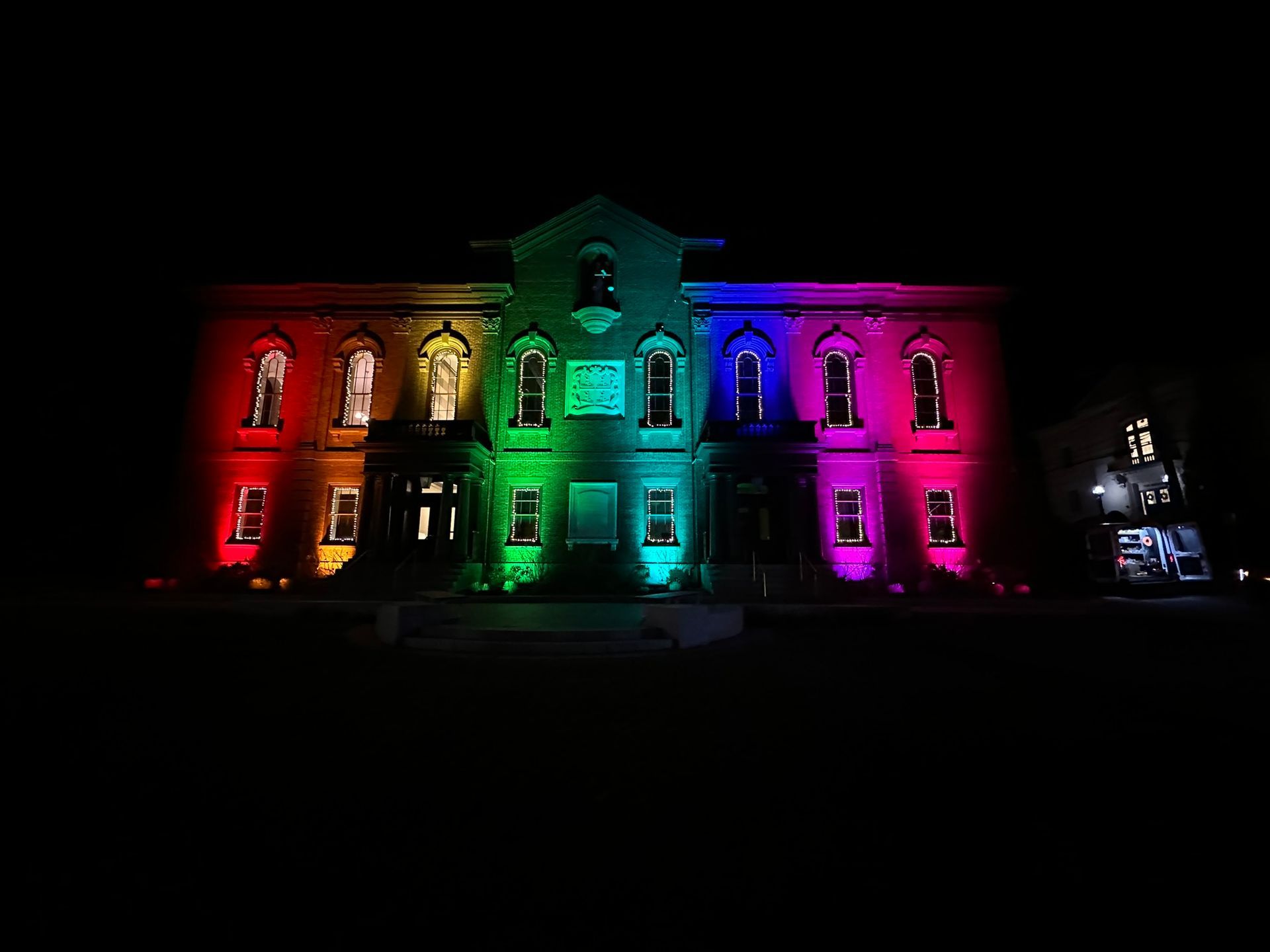 Building illuminated with rainbow colors at night.