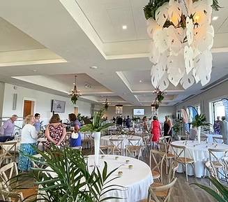 Interior of event space with round tables, guests, and decorative lighting.