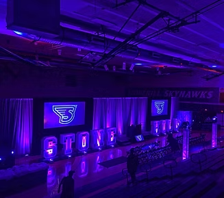Gymnasium set for an event with purple lighting. Displays 