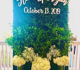 Greenery backdrop with white florals, the names 