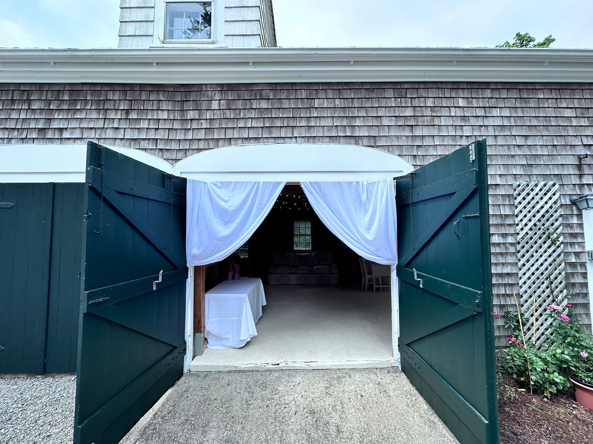 Green barn doors open to interior with white draped entrance.