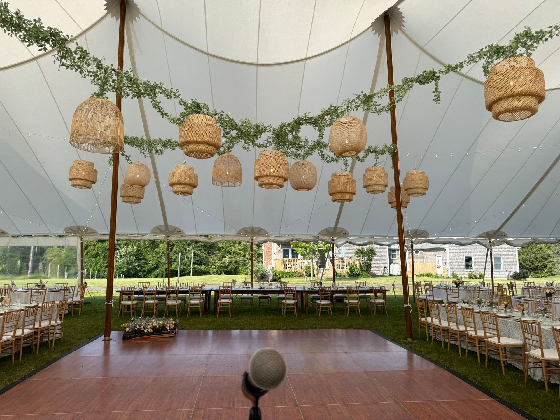 Wedding reception tent with hanging lanterns, floral garlands, tables, and a dance floor.