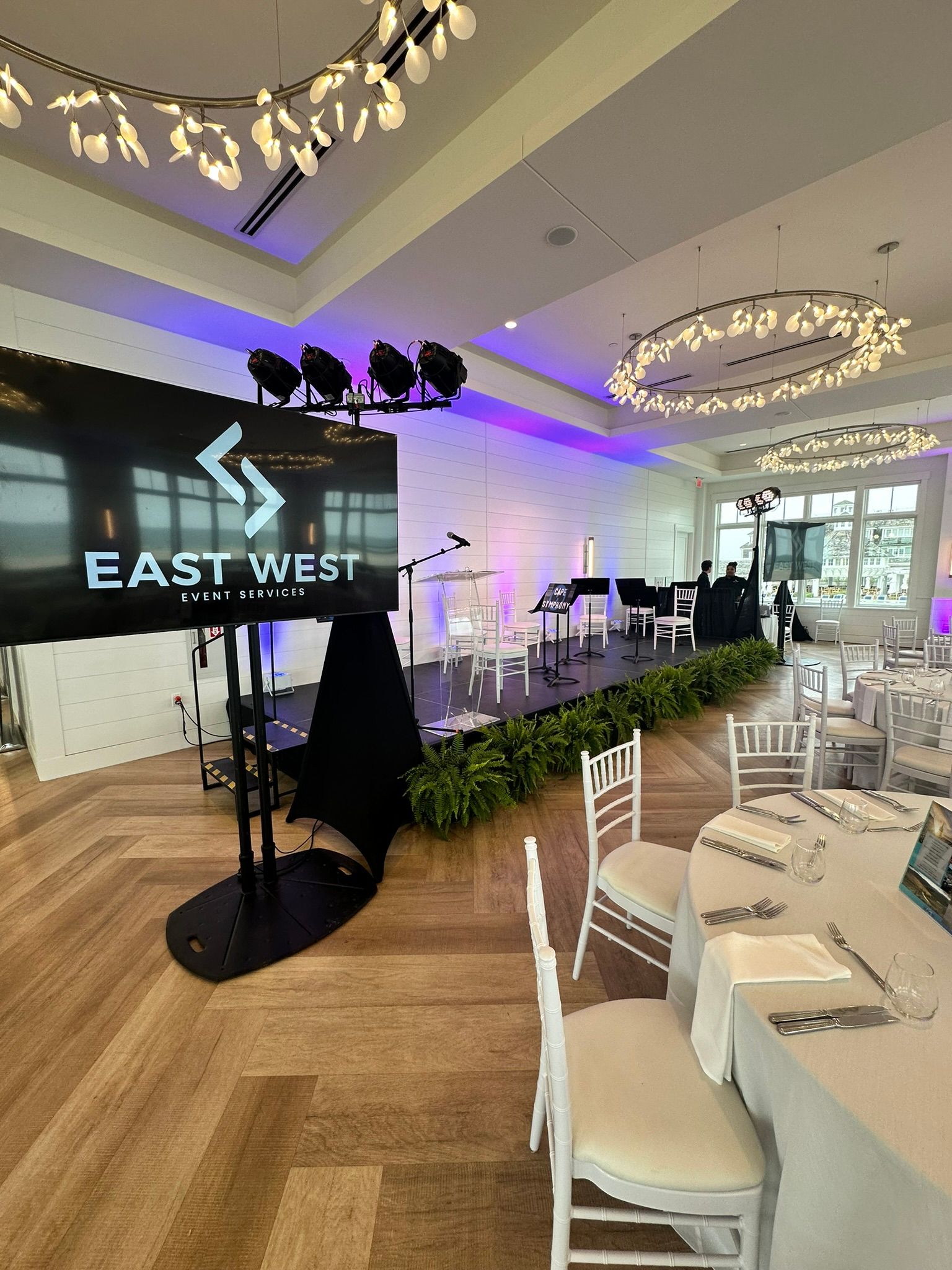 Event space with a stage, screen, and tables set for dining.