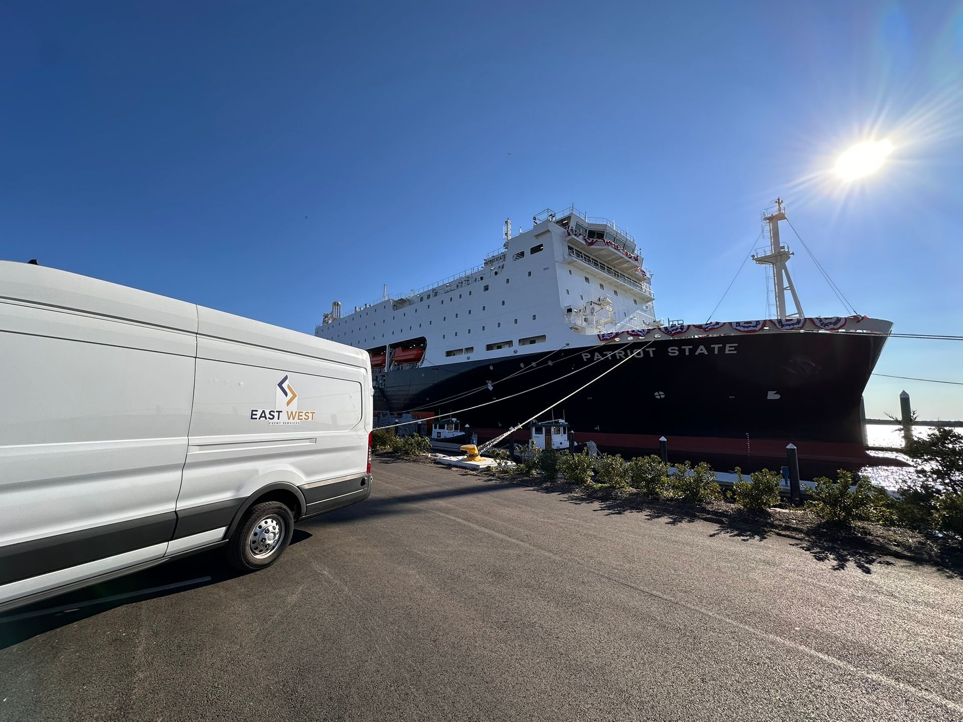 White van parked near a large docked ship named 
