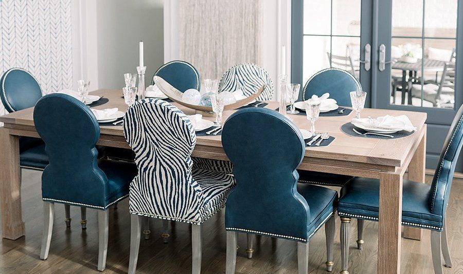 A dining room table with blue chairs and plates on it.