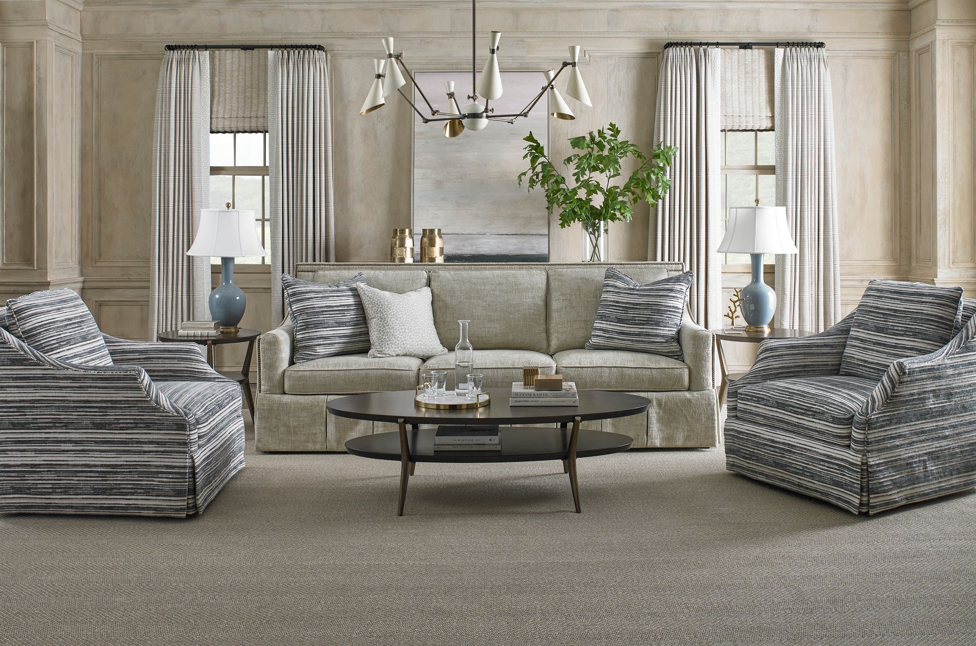 A living room with a couch , two chairs , a coffee table and a chandelier.