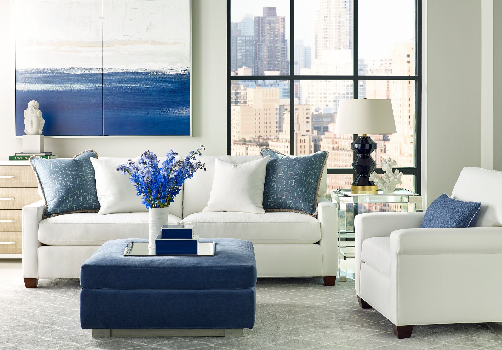 A living room with white furniture and a blue ottoman