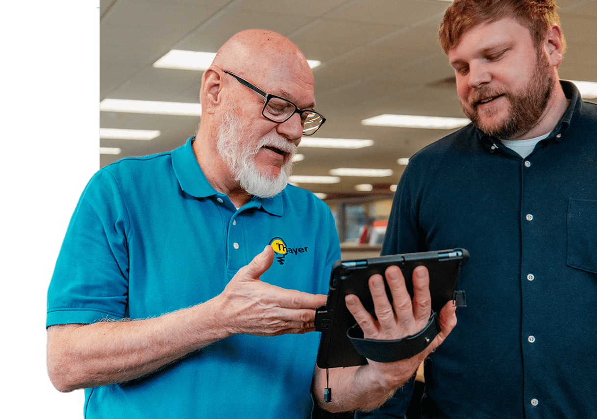 Two men are looking at a tablet together.