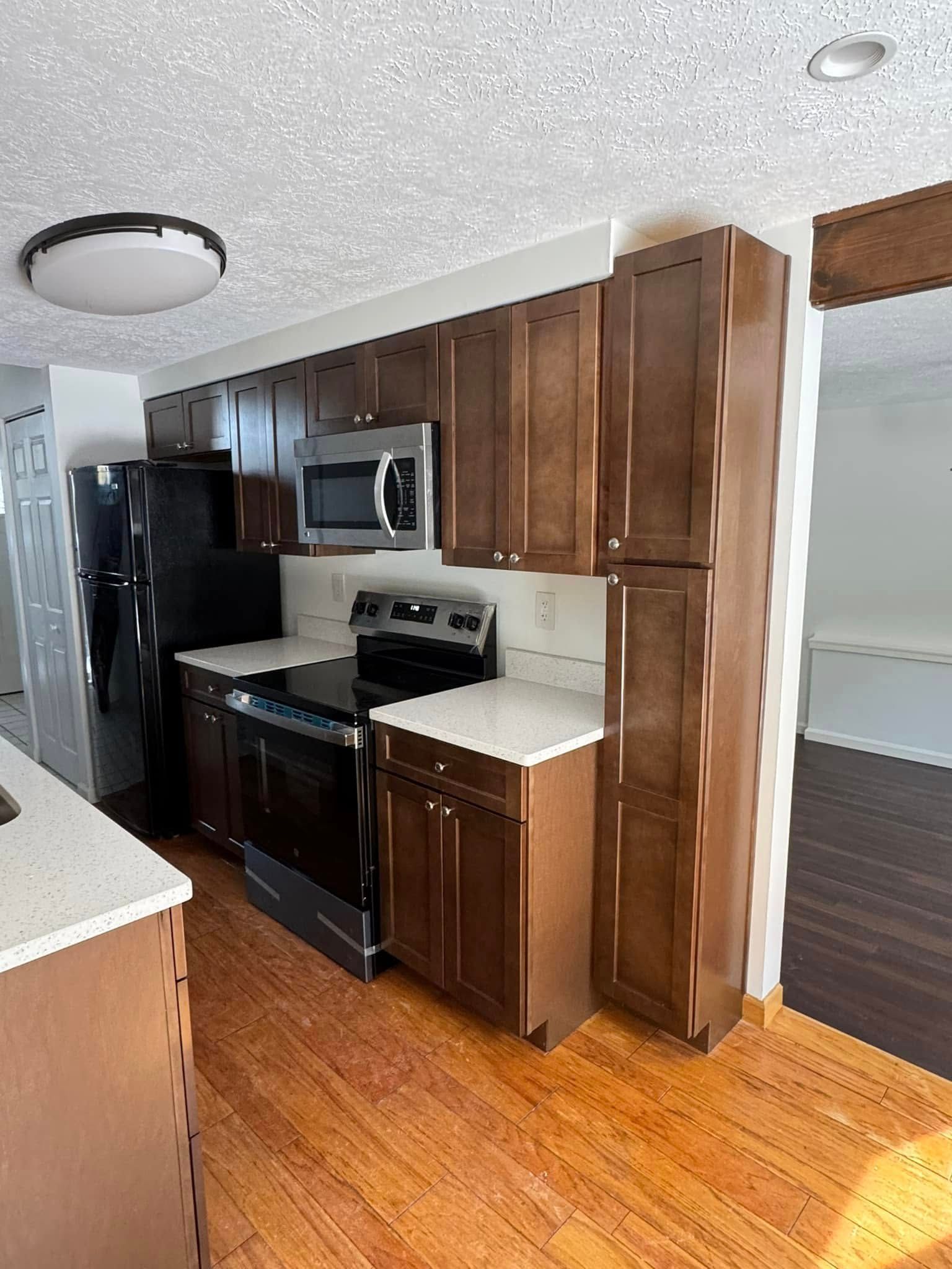 Kitchen with brown cabinets, stainless steel appliances, and wood flooring.