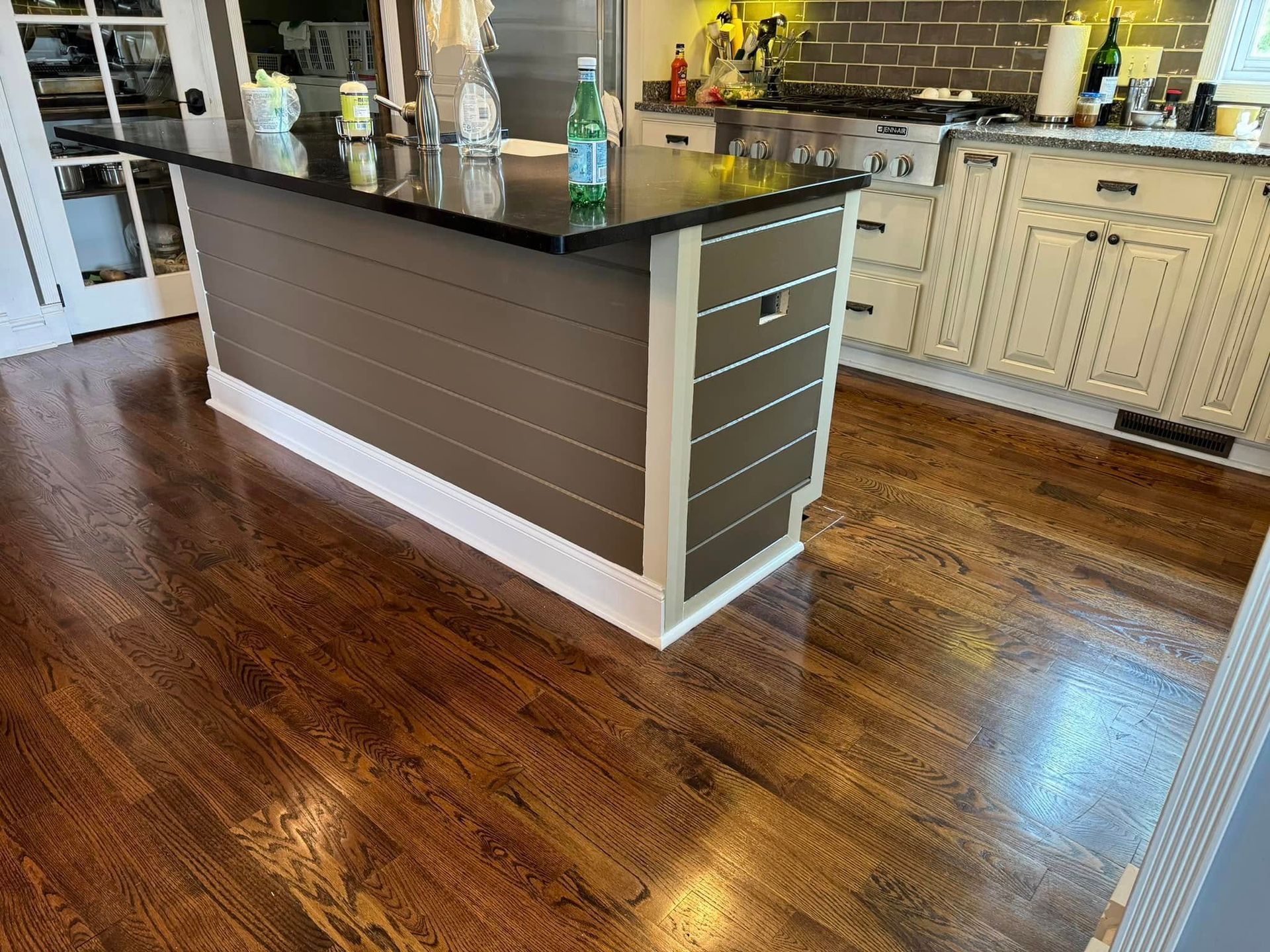 Kitchen island with dark countertop, brown paneling, and white trim, on wood floor.