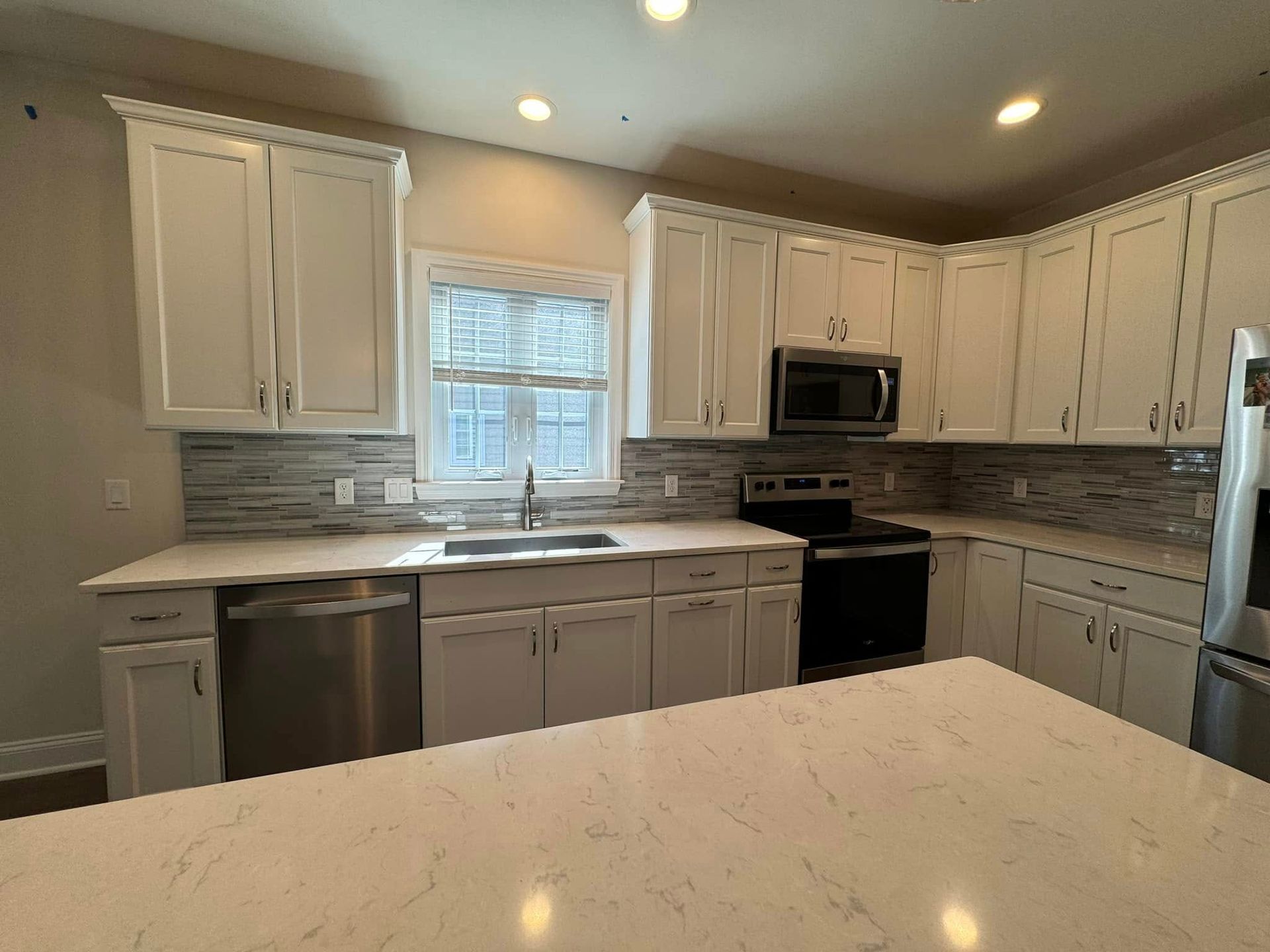 White kitchen with stainless steel appliances, white cabinets, and a kitchen island.