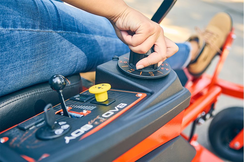 Person operating a Bad Boy zero-turn lawnmower, focused on controls.