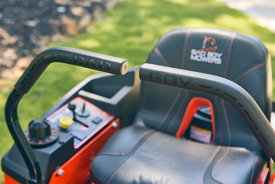 Close-up of a Bad Boy zero-turn lawnmower seat and controls with black handles.