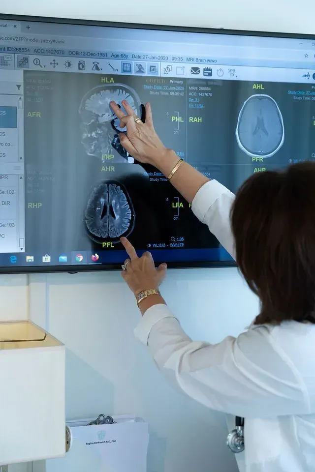 Doctor pointing to brain scan on a large medical monitor in a hospital setting