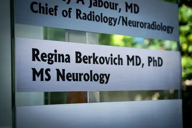 Clinic directory sign listing Regina Berkovich, MD, PhD, MS Neurology, and radiology chief A. Jabour, MD