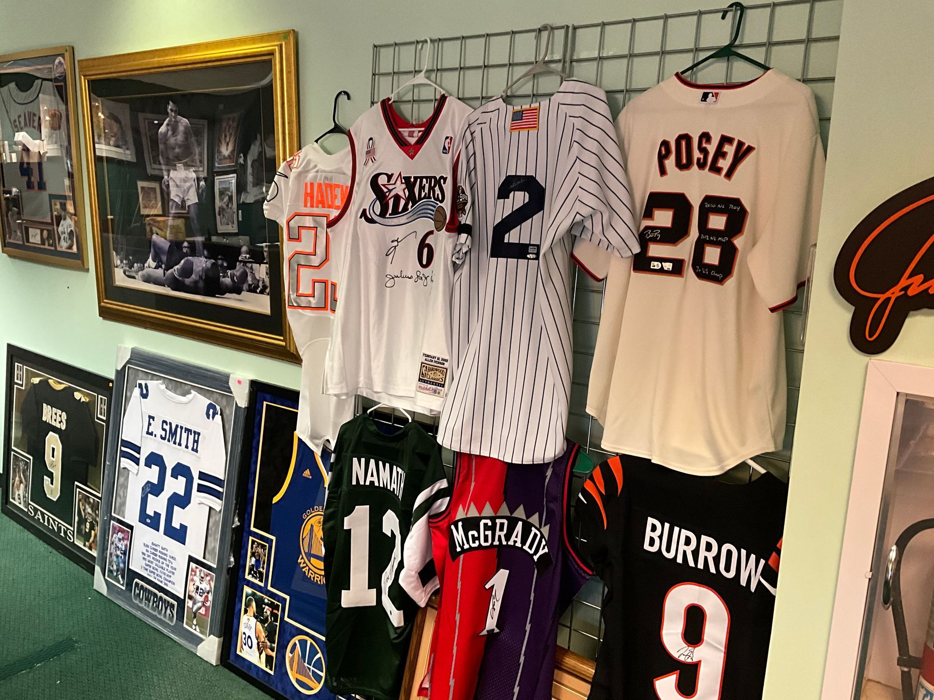 Sports jerseys and framed memorabilia on display. Variety of team colors and numbers are visible.