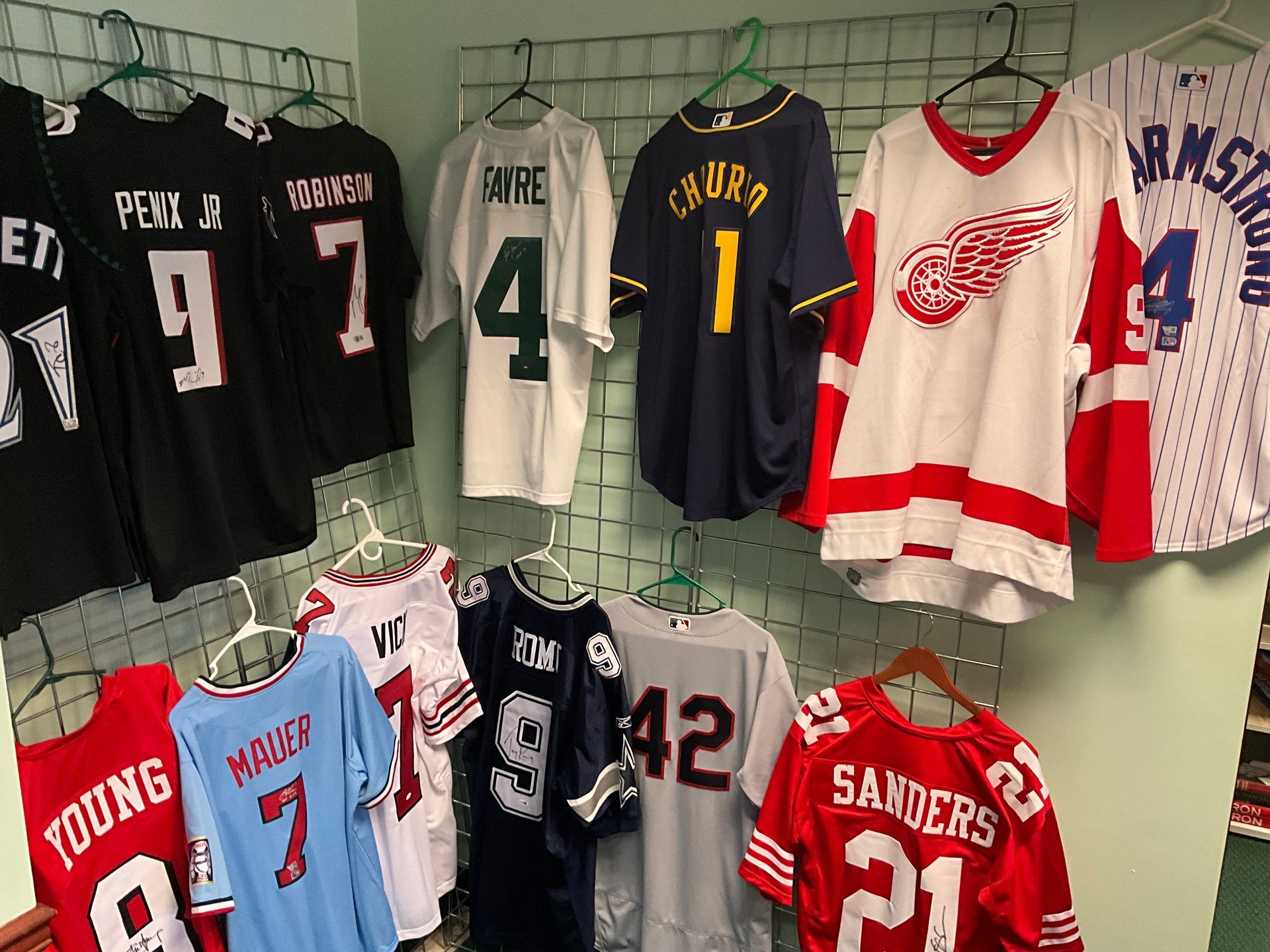 Collection of sports jerseys hanging on a wire rack. Jerseys are various colors, with names and numbers.