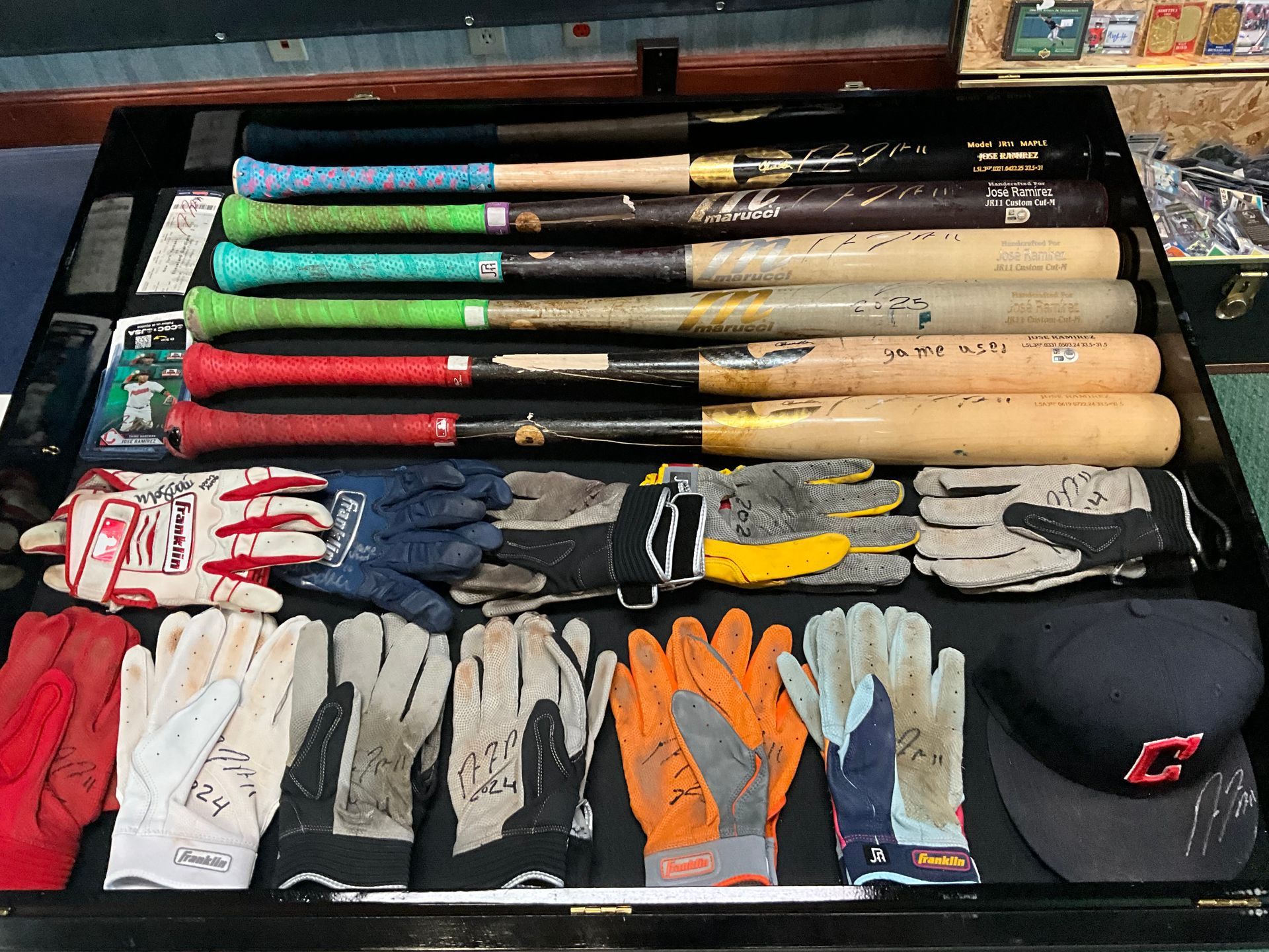 Baseball bats and gloves arranged in rows on a table. Various colors and signatures are visible.