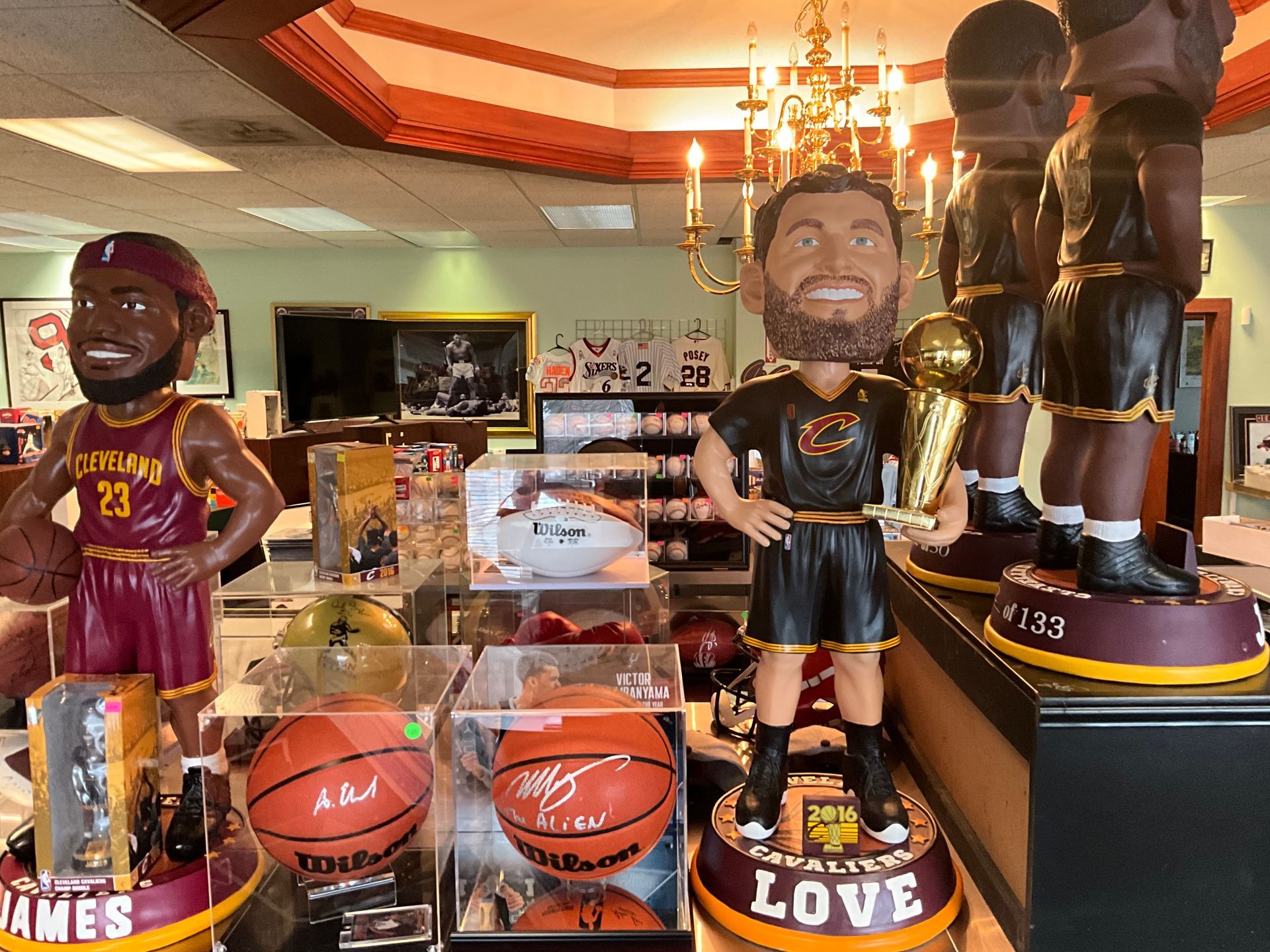 Bobbleheads of Cleveland Cavaliers players with basketballs and trophy on display.
